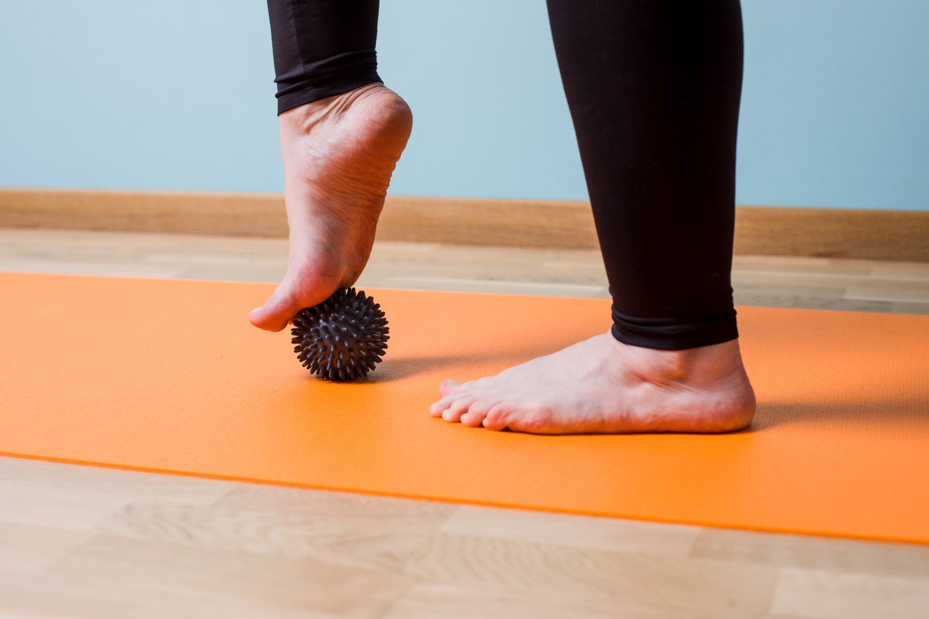 Massaging Bare Feet with Small Knobbed Ball